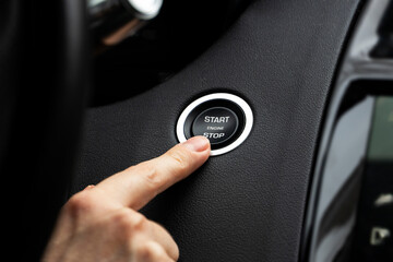 Women activates button to start and stop for car engine, pressing start engine button on a modern...
