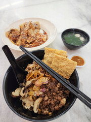 Popular Chinese meal. Dried Pan Mee with Stir-Fry Minced Pork, Crispy Anchovies, Mushroom Slices and Pork Meat Balls. Found in all eatery shops, hand operated noodle machine to flatten and cut