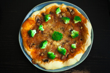pizza with vegetables and a portrait of a baby biting pieces of pizza