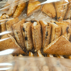 Cookies with raisins and cream close-up in the package. Sweets for tea. Background. Cookies sprinkled with sugar triangular shape.