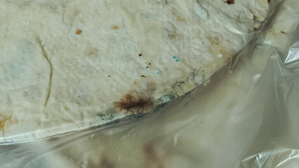 Mold on pita bread in packaging. Expired shelf life of baked goods, bread products. Background....