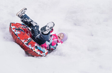 Happy girl slid down on snow tube and funny fell upside down. Winter fun, leisure. Hello winter