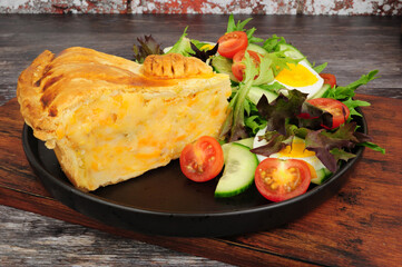 Shortcrust pastry cheese and potato filled pie slice with fresh egg salad meal