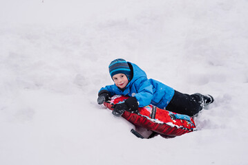 Happy boy on a snow tube in winter. Winter fun, leisure. Hello winter