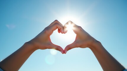 Fototapeta premium Hands forming heart shape, expressing love, against bright sunny sky
