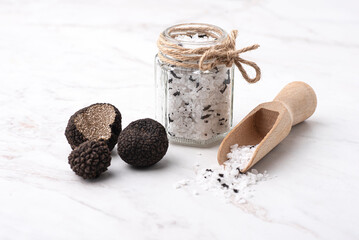 Truffle salt and truffle on the white table, how to preserve the aroma and taste of black truffle. Preserving black truffle. Delicacy condiment for flavoring dishes, front view