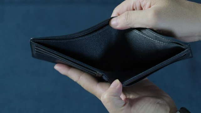 Businessman displaying an empty wallet to highlight financial difficulties