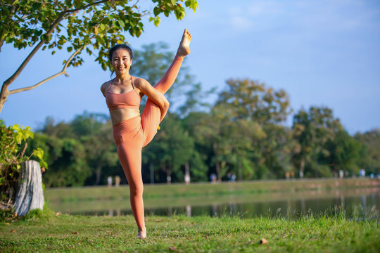 Young woman practicing yoga on soft green grass beside the lake. Young woman practicing yoga in nature. Healthy lifestyle. Concept of vitality, balance, mindfulness, Zen energy, calmness, relaxation, 