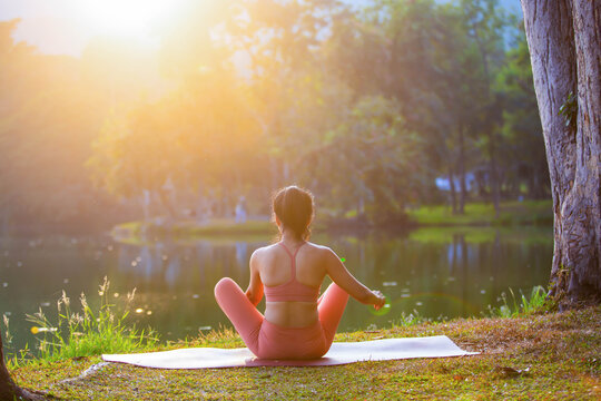 Young woman practicing yoga on soft green grass beside the lake. Young woman practicing yoga in nature. Healthy lifestyle. Concept of vitality, balance, mindfulness, Zen energy, calmness, relaxation, 