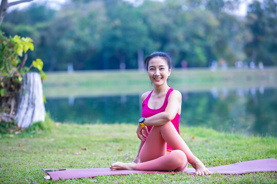 Young woman practicing yoga on soft green grass beside the lake. Young woman practicing yoga in nature. Healthy lifestyle. Concept of vitality, balance, mindfulness, Zen energy, calmness, relaxation, 