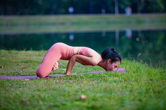 Young woman practicing yoga on soft green grass beside the lake. Young woman practicing yoga in nature. Healthy lifestyle. Concept of vitality, balance, mindfulness, Zen energy, calmness, relaxation, 