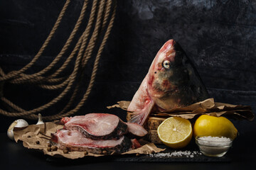 Sliced ​​raw fish on dark background. Fish head and slices of raw fish