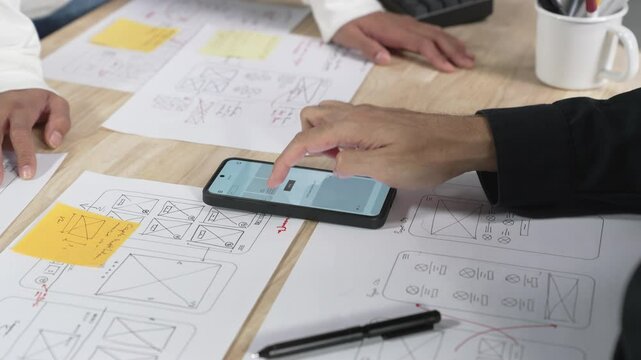 UX UI designers discussing and brainstorming on wireframes for a website and mobile app prototype, in the concept of website and mobile application design concept.