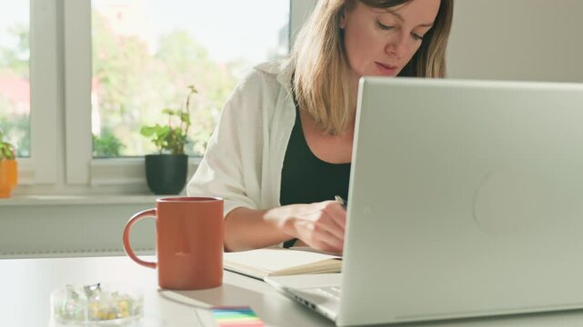 Focused woman working on laptop at home, hands typing on keyboard. Concept of freelance and remote work