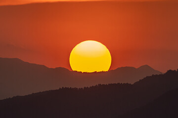 Obraz premium 夕焼けの中、山に沈む太陽