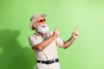 Elderly adventurer enjoying safari style in casual shorts and beige shirt with green background © deagreez