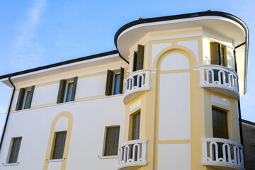 Fototapeta premium Typical Italian architecture, white building with green windows and beautiful balcony. European style facade. 