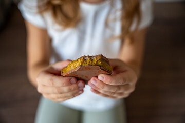 Dubai chocolate with pistachio paste and kataifi dough in hands of little girl. Confectionery handmade sweets at home in the kitchen. 