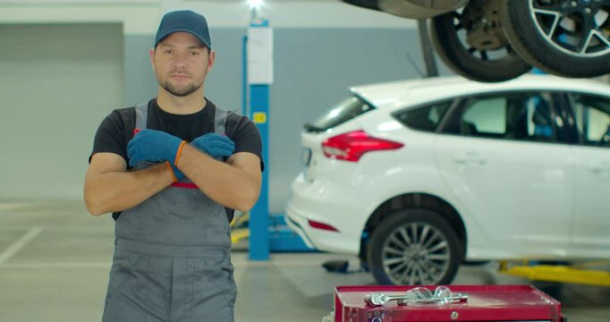 Portrait of a young beautiful car mechanic in a car workshop, in the background of service.