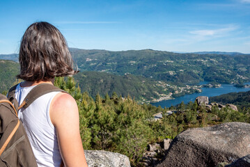 Naklejka premium A hiker enjoying the view on lake Cavado in the Peneda Geres National Park, seen from Voltas de Sao Bento viewpoint, Portugal