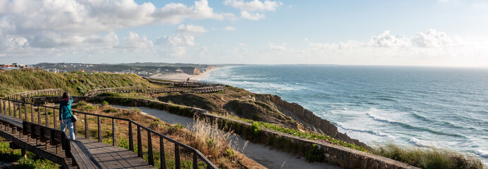 A young woman walking on a boardwalk at the Portuguese coast near Foz do Arelho © imagoDens