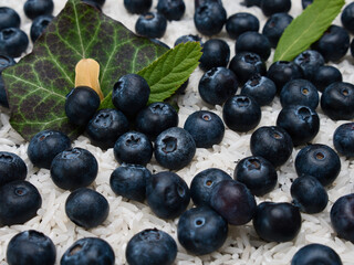 Blueberries Lying on Rice Grains with Green Leaves in the Background