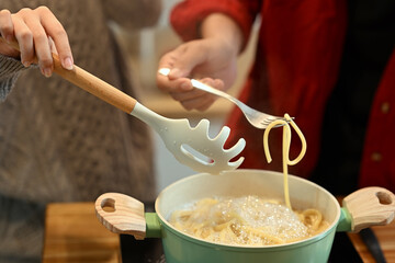 Young married couple preparing delicious pasta on Christmas Day