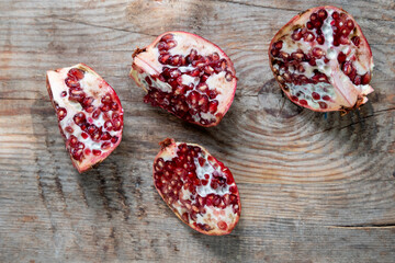 pomegranate divided into 4 pieces, on a wooden background, top view