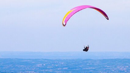 Paraglider flying in the air over hills. Aerial view of flying on a sunny day. 