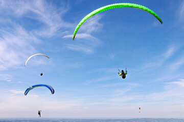 Paraglider flying in the air over hills. Aerial view of flying on a sunny day. 