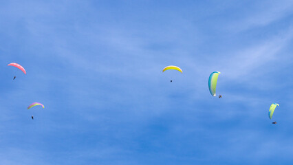 Paraglider flying in the air over hills. Aerial view of flying on a sunny day. 