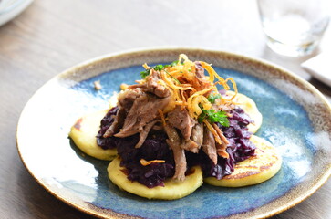 The deep purple of the red cabbage contrasts with the crispy, golden-brown potato pancakes and the succulent, slow-cooked duck meat