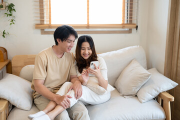 Young cheerful love couple sharing content on a smartphone together at home