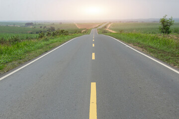 Natural scenery with asphalt road in the middle with horizon landscape line at sunset