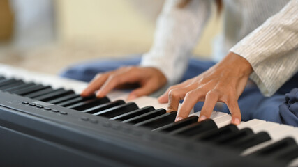 Obraz premium Close up female musician playing an electronic piano in living room