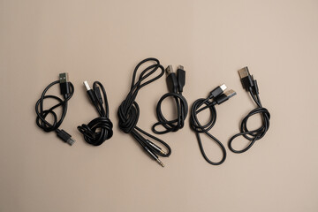 Various black cables and connectors neatly laid out on a beige background, showcasing different types of USB and audio cables
