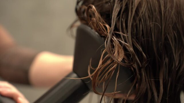 Hairdresser drying dark curly hair with a hair dryer with a diffuser