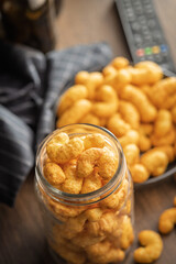 Puffed crispy Peanut flips in jar on wooden table.