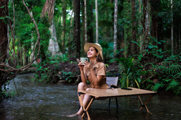 woman sitting on a chair in the stream flowing and drinking coffee  in her hand, relaxtion in holiday concept.