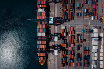 commercial port in deep sea load and unloading cargo from container ship import export by crane for distributing goods by trailers transport logistic  to customers and dealers, aerial top view