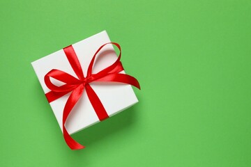 Beautiful gift box tied with red bow on color background 