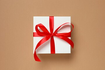 Beautiful gift box tied with red bow on color background 