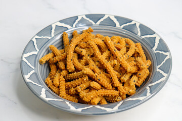 Crunchy fried homemade Chakli sticks with sesame seeds. Chakli is a savory snack from India made out of rice, mixed yellow and green lentils along with spices. Mostly eaten during Diwali festival