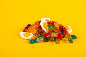 Assorted gummy candies, Juicy colorful jelly sweets. Gummy candies on yellow background