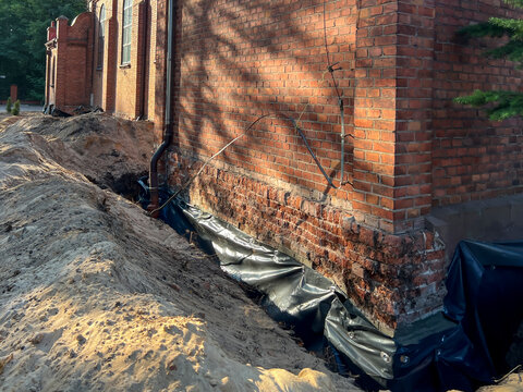 Securing the foundations of existing, old buildings against moisture. Excavation, cleaning, reinforcement of joints, insulation and backfilling with earth