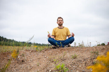 Bearded man doing yoga on a hill after hard working day. Concept of healthy lifestyle, retreat in nature, relaxation, connection with nature, meditation.
