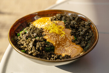 Vegetarian spinach salad closeup. Fried spinach with nori and tahini, vegan dish in sunlight