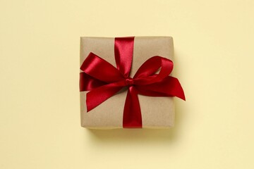 Beautiful gift box tied with red bow on color background 