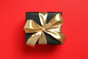 Beautiful gift box tied with golden bow on color background 