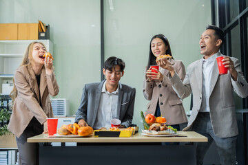 Asian business team are excited business success with inspiration from their excellent financial results, celebration successful deal with champagne and pizza in the workplace.